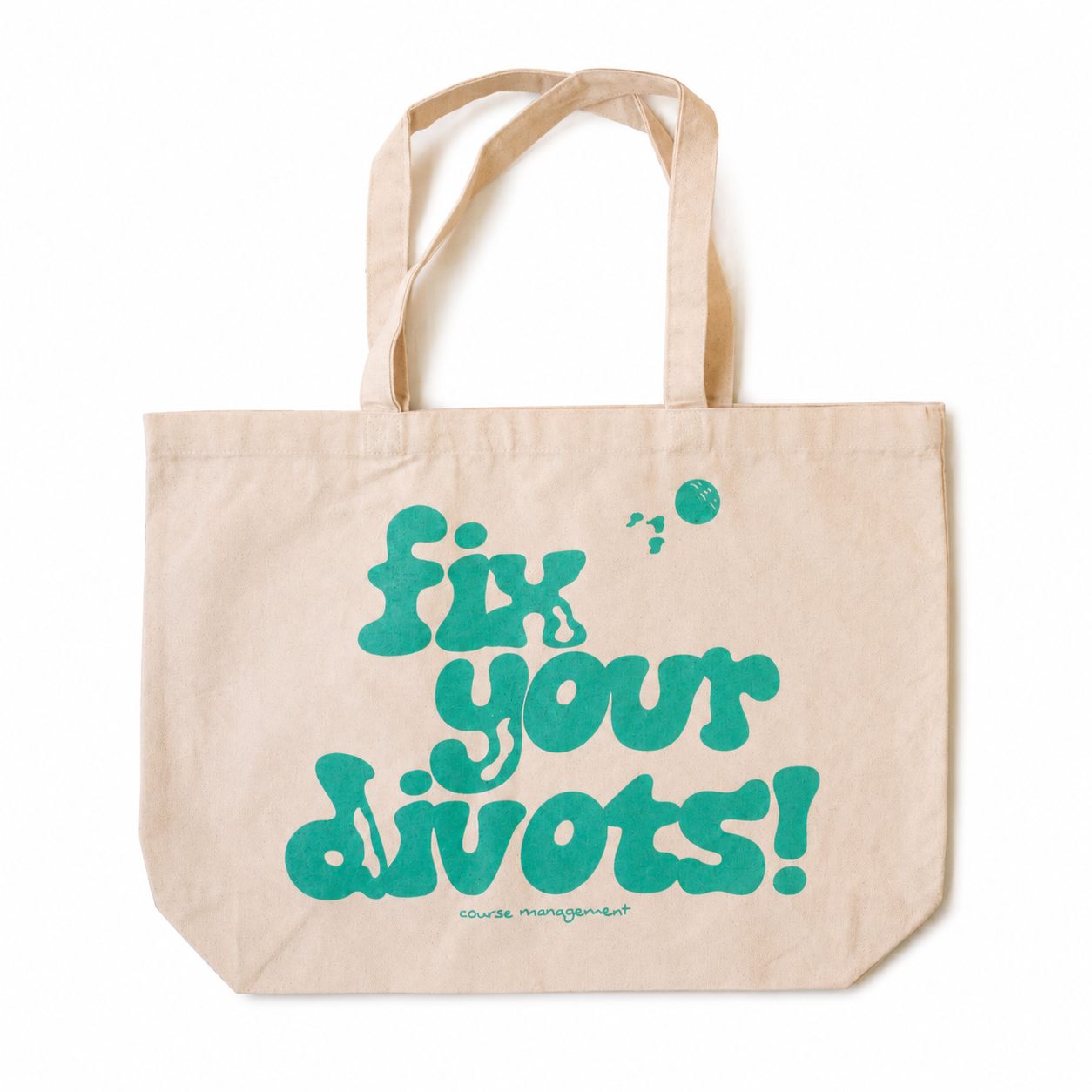 A natural beige canvas tote bag with the phrase 'fix your divots!' printed in a bold teal-green font on the front, set against a plain white background.