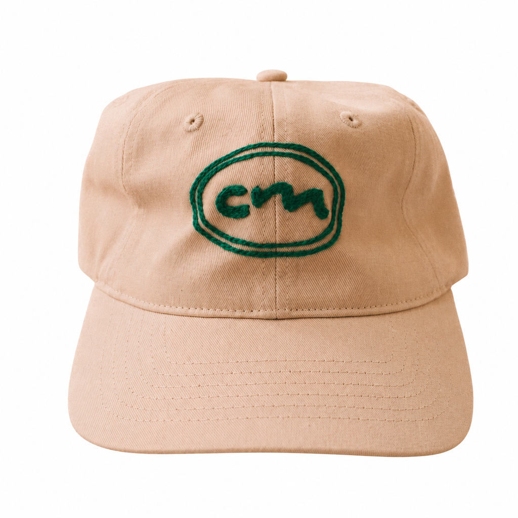 A white baseball cap with a green embroidered oval logo on the front, photographed against a plain white background.