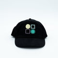 A black baseball cap featuring four embroidered geometric shapes on the front.