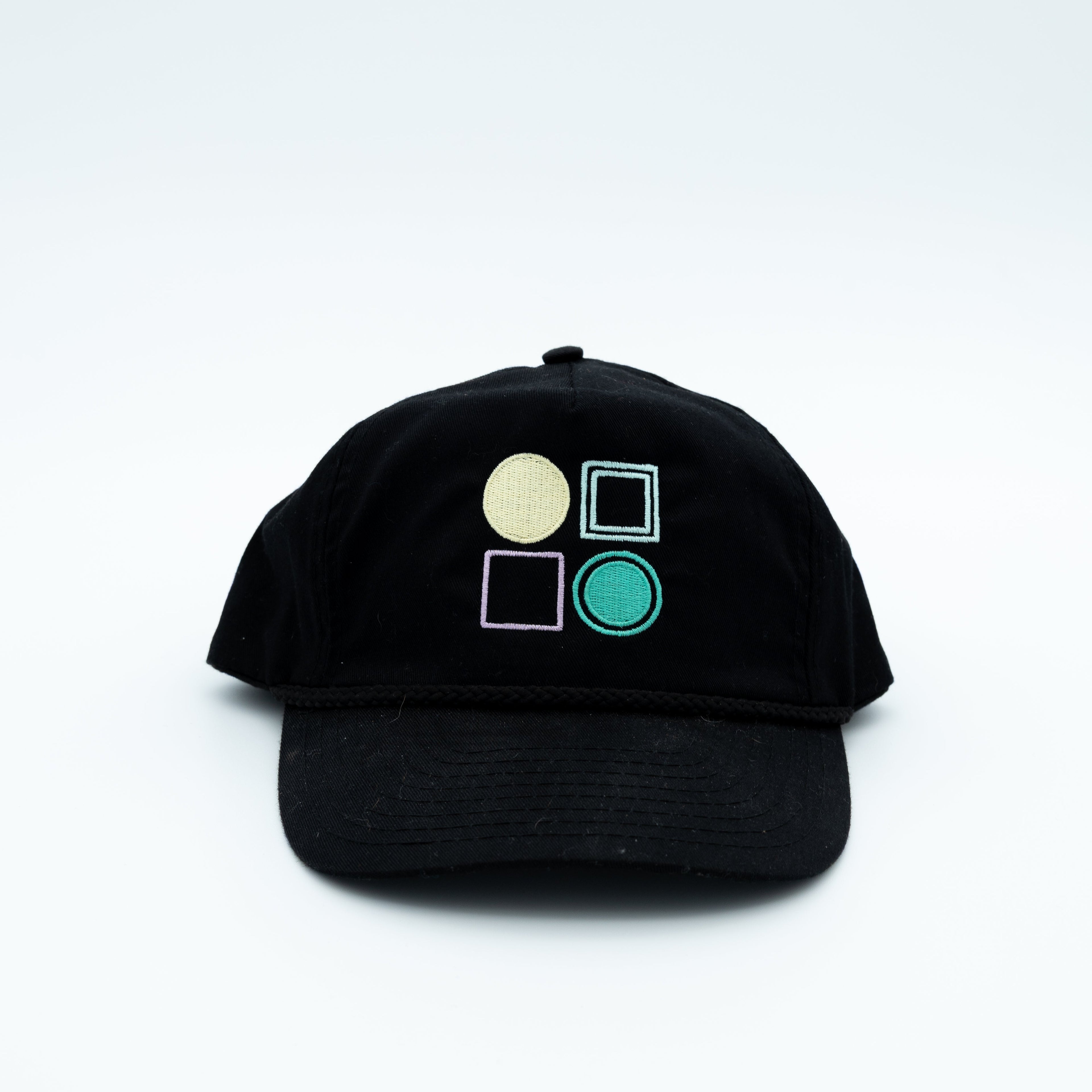 A black baseball cap featuring four embroidered geometric shapes on the front.