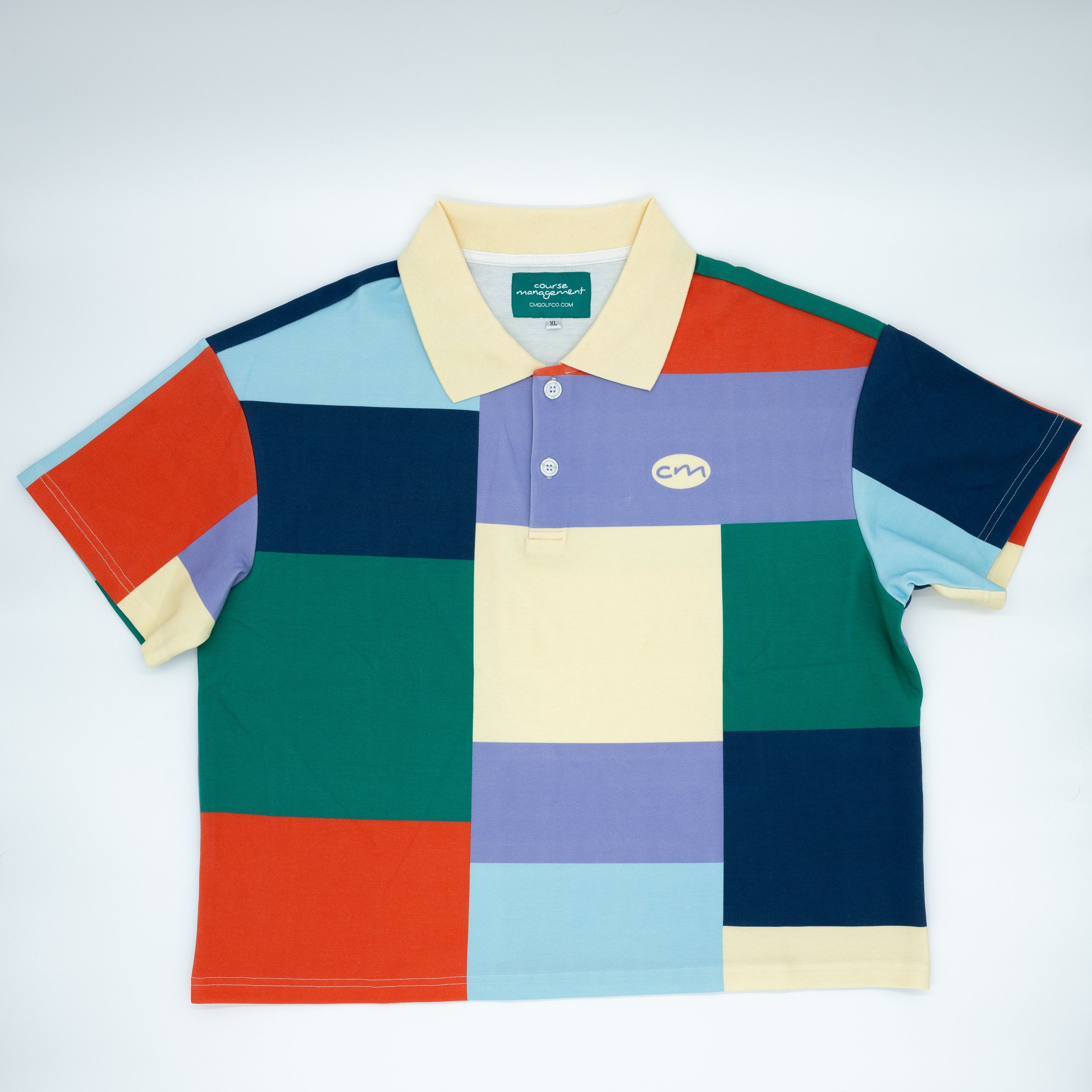 A short-sleeve polo shirt with a colorful patchwork block pattern in red, orange, green, blue, purple, and cream, featuring a light yellow collar and a small Course Management logo on the chest.