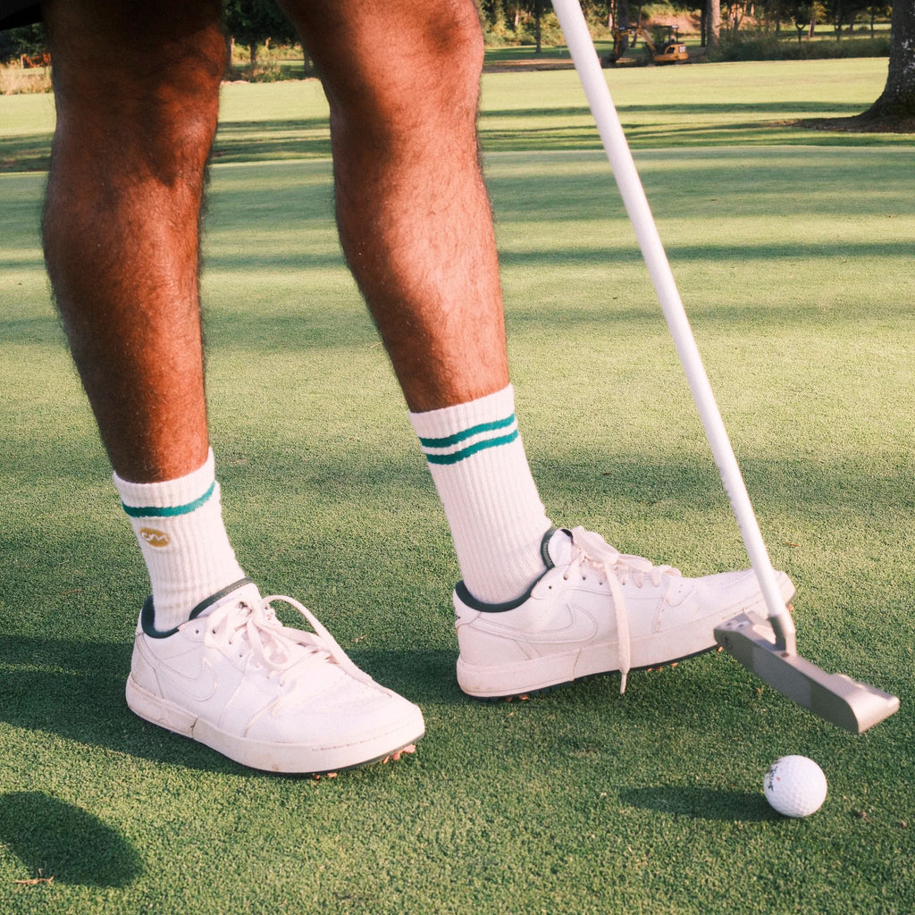 Man holding golf clubs wearing white crew socks.