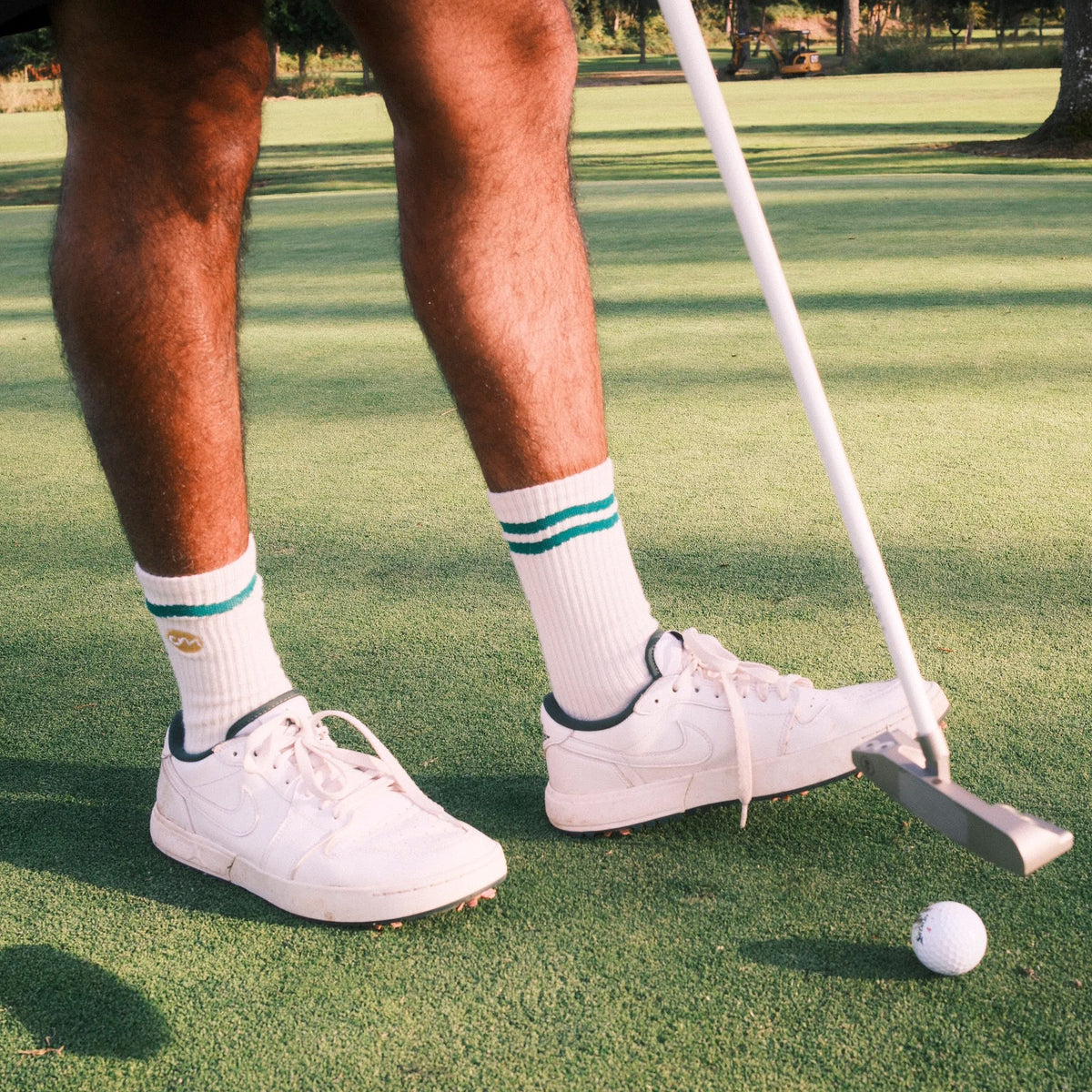 Man holding golf clubs wearing white crew socks.